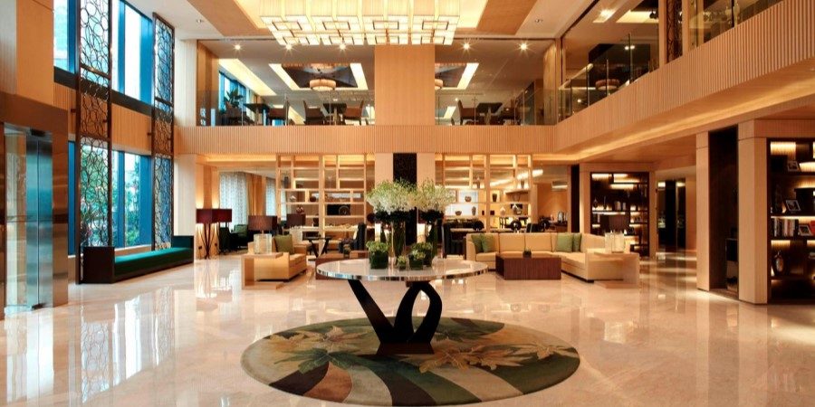 The lobby of a hotel showcasing a grand chandelier, with modern furnishings and a welcoming atmosphere.